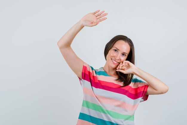 Jeune femme agitant la main pour dire au revoir en t-shirt et à la bonne humeur. vue de face.