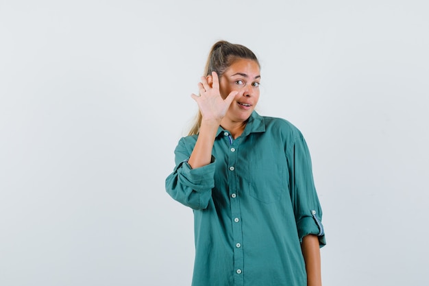 Jeune femme en agitant la main pour saluer en chemise bleue et à la satisfaction