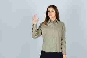 Photo gratuite jeune femme agitant la main pour saluer en chemise, jupe et à la gaieté, vue de face.
