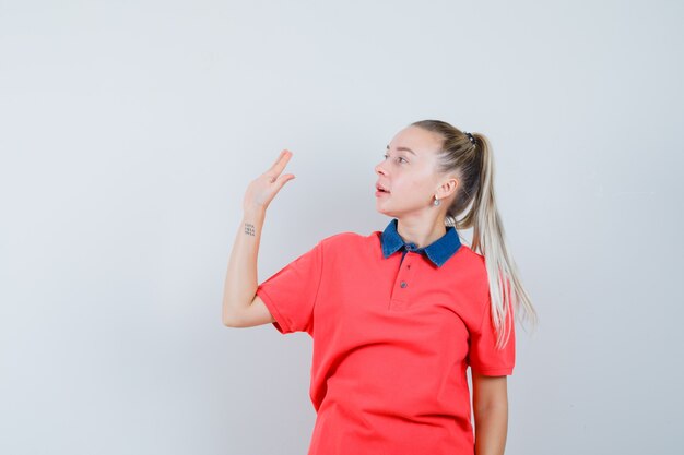 Jeune femme en agitant la main tout en regardant de côté en t-shirt