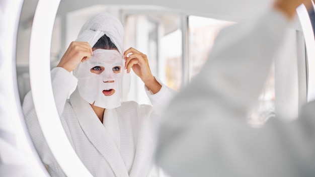 Jeune femme à l'aide d'un masque de beauté