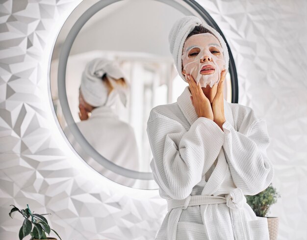 Jeune femme à l'aide d'un masque de beauté