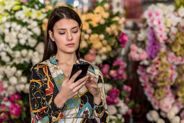 Photo gratuite jeune femme à l'aide de smartphone en serre