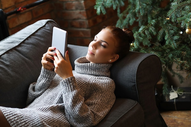 Jeune femme à l'aide de tablette sur le canapé