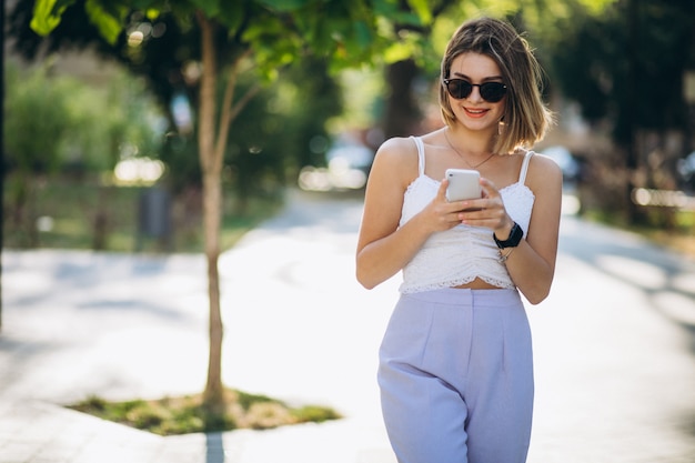 Jeune femme à l'aide de téléphone dans le parc