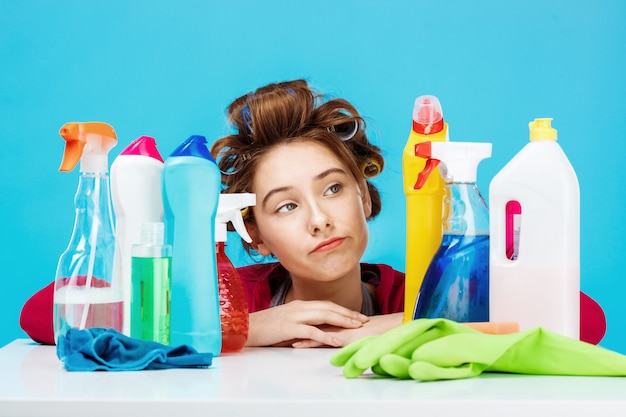 Photo gratuite jeune femme a l'air fatiguée assis derrière la table avec des outils de nettoyage