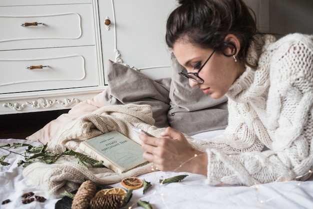 Jeune femme allongée sur une couverture et utilisant un smartphone