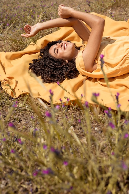 Jeune femme allongée sur un drap jaune dans la nature