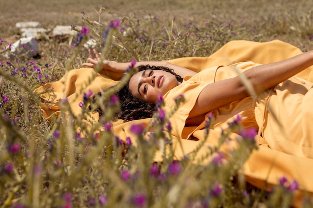 Jeune femme allongée sur un drap jaune dans la nature