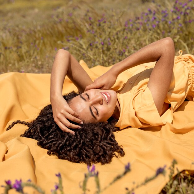 Jeune femme allongée sur un drap jaune dans la nature