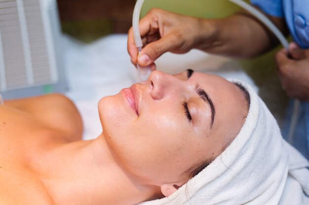 Jeune femme allongée sur la table du cosmétologue au cours de la procédure de rajeunissement