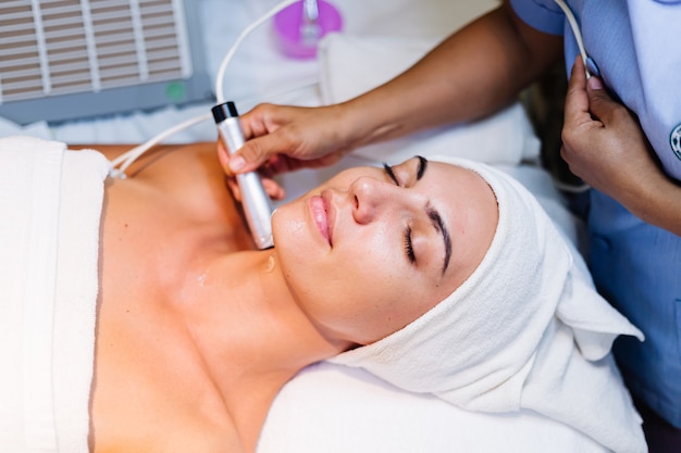 Jeune femme allongée sur la table du cosmétologue au cours de la procédure de rajeunissement