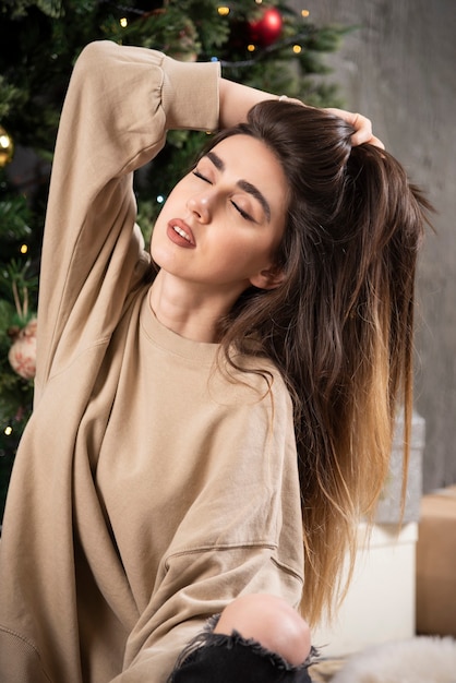 Jeune femme allongée sur un tapis moelleux près de l'arbre de Noël.