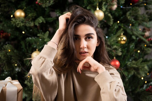 Jeune femme allongée sur un tapis moelleux près de l'arbre de Noël.