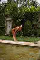 Photo gratuite jeune femme à l'apparence positive du corps pratiquant le yoga seule sur le pont au bord de la piscine de l'île tropicale de bali, en indonésie. sport, fitness, concept de mode de vie sain.