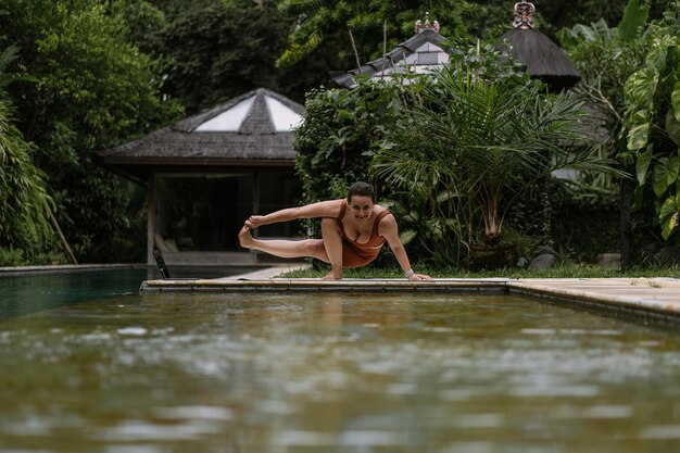 Jeune femme à l'apparence positive du corps pratiquant le yoga seule sur le pont au bord de la piscine de l'île tropicale de Bali, en Indonésie. Sport, fitness, concept de mode de vie sain.