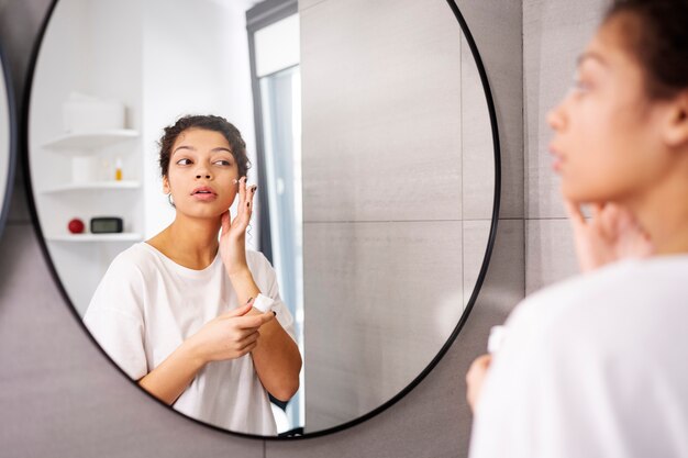 Jeune femme appliquant une crème pour le visage