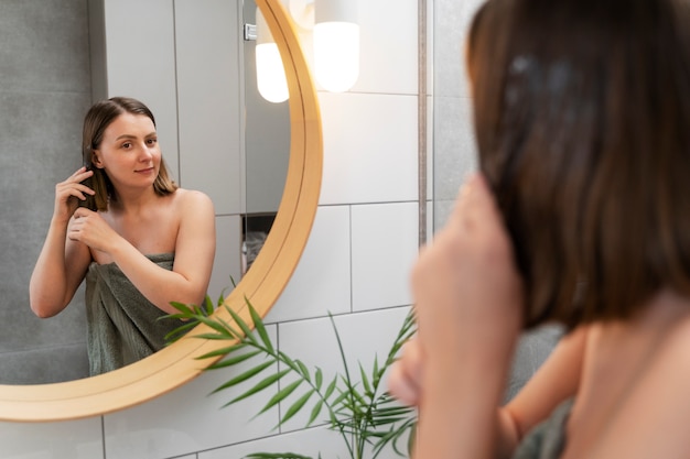 Jeune femme appliquant un produit antipelliculaire