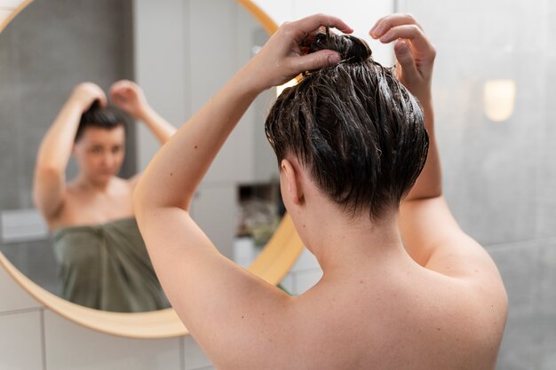 Jeune femme appliquant un produit antipelliculaire