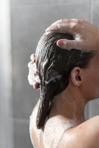 Jeune femme appliquant un produit antipelliculaire