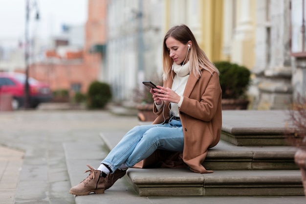 Jeune femme appréciant la musique sur ses écouteurs dans la ville