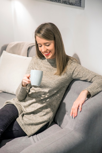 Jeune femme apprécie une tasse de café ou un thé à la maison en fermant les yeux avec plaisir car elle savoure le goût