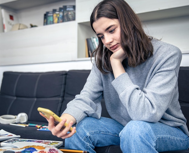 Une jeune femme apprend à dessiner à l'aide d'une vidéo dans un smartphone