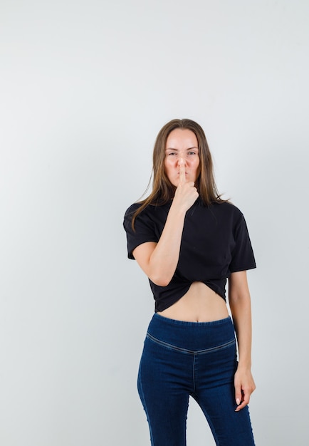 Jeune femme en appuyant sur le nez avec le doigt en chemisier noir, pantalon et à la sombre