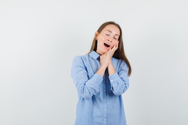 Jeune femme appuyée sur les paumes comme oreiller en chemise bleue et à la somnolence