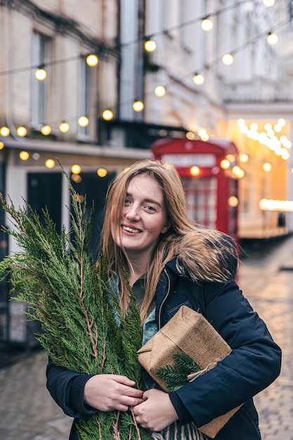 Jeune femme avec un arbre de Noël et une boîte-cadeau sur un arrière-plan flou