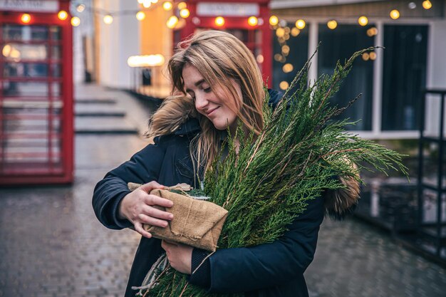 Jeune femme avec un arbre de Noël et une boîte-cadeau sur un arrière-plan flou