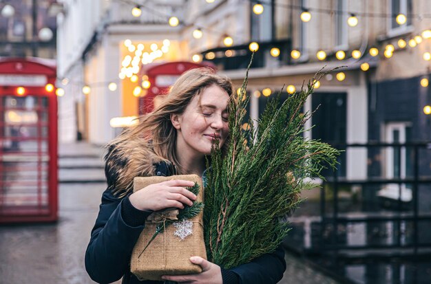 Jeune femme avec un arbre de Noël et une boîte-cadeau sur un arrière-plan flou