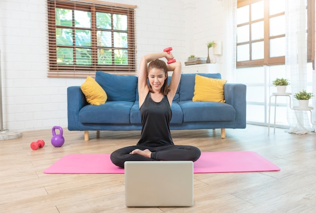 Jeune femme asiatique en bonne santé dans l'entraînement de vêtements de sport à la maison, exercice, ajustement, faire du yoga. concept de remise en forme sport à domicile