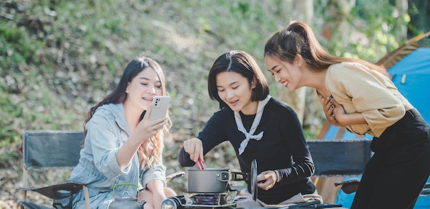 Une jeune femme asiatique cuisine et son amie aime préparer le repas en pot Ils parlent et rient avec plaisir ensemble en camping dans un parc naturel