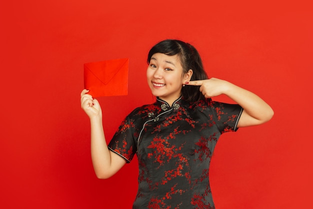 Jeune femme asiatique avec enveloppe rouge isolé sur mur rouge