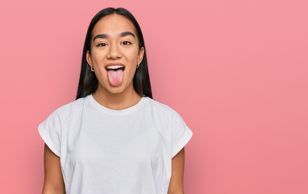 Photo gratuite jeune femme asiatique portant un t-shirt blanc décontracté qui sort la langue heureuse avec le concept d'émotion d'expression drôle