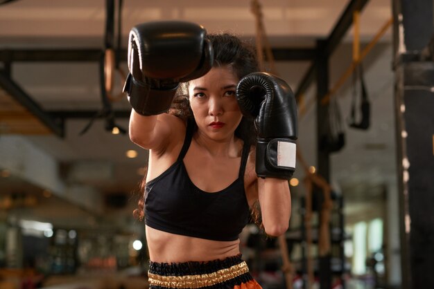 Jeune femme asiatique s'entraînant dans des gants de boxe à la pratique du Muay Thai