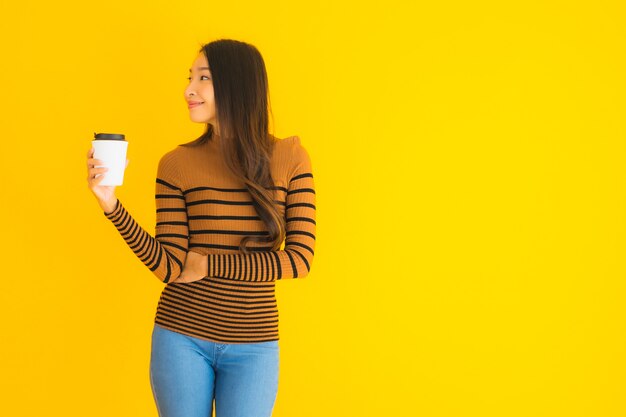 jeune femme asiatique avec sac à dos et tasse de café à la main sur jaune