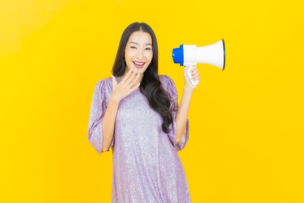 jeune femme asiatique souriante avec mégaphone sur jaune