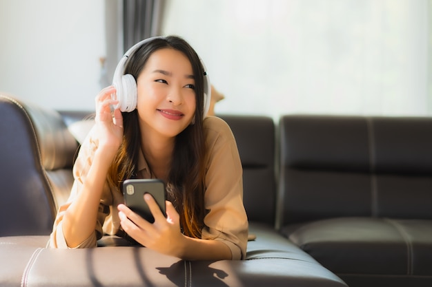 jeune femme asiatique, utilisation, smartphone, sur, sofa, à, écouteurs