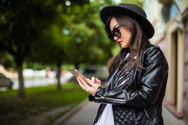 Jeune femme asiatique utilise un téléphone intelligent dans la rue