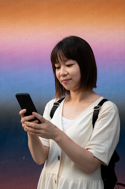 Photo gratuite jeune femme asiatique vérifiant son téléphone à l'extérieur