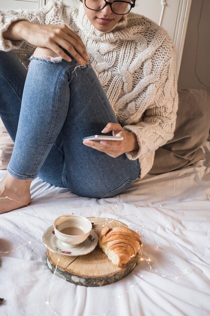 Jeune femme assise sur une couverture avec café et croissant