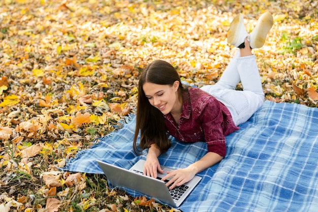 Photo gratuite jeune femme assise sur une couverture dans le parc