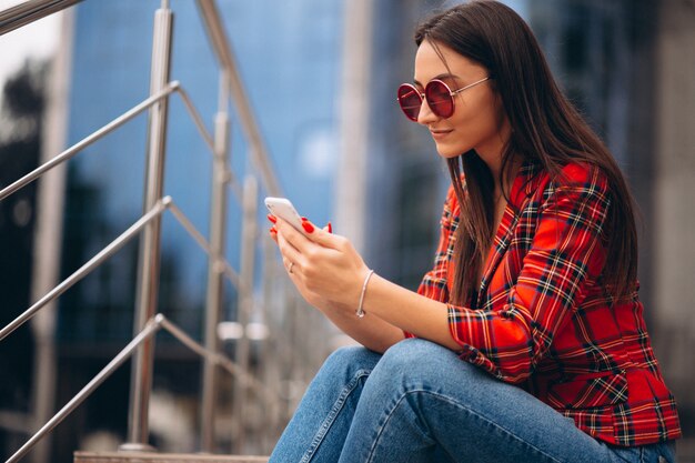 Jeune femme assise dans les escaliers et parlant au téléphone