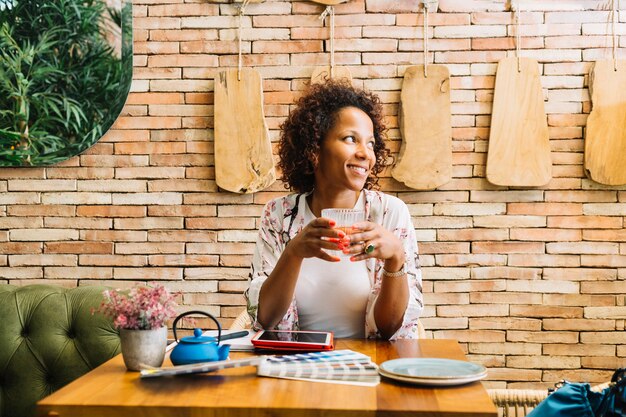 Jeune femme assise dans le restaurant tenant un verre de jus