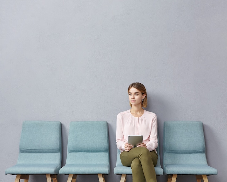 Photo gratuit une jeune femme assise dans la salle d'attente.