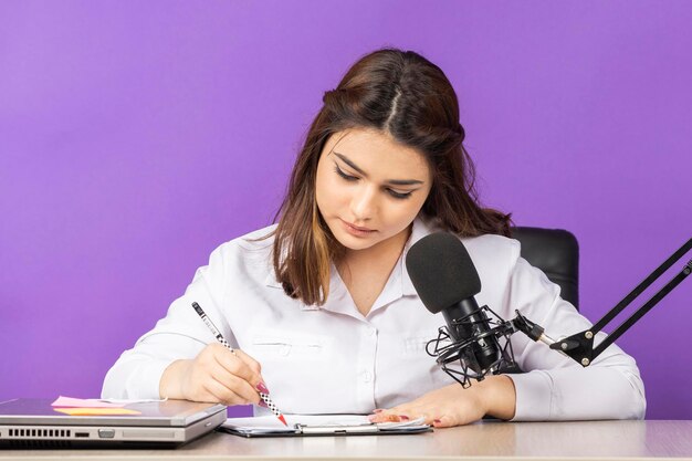 Jeune femme assise derrière le bureau et écrivant ses notes Photo de haute qualité