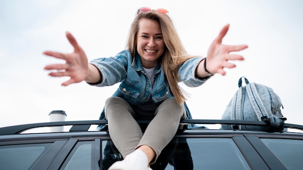 Jeune femme assise sur le dessus de la voiture