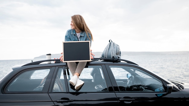 Jeune femme assise sur le dessus de la voiture